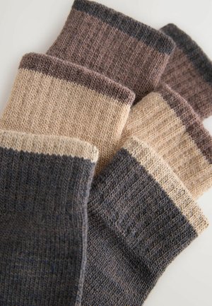 Drei Paar strukturierte Socken in verschiedenen Braun- und Beigetönen, mit gerippten Bündchen und kontrastierenden Farbstreifen an den Oberteilen.