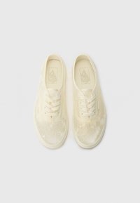 Šněrovací tenisky v odstínu off-white, s krajkovým vzorem, kulatou špičkou a gumovou podrážkou s texturovaným gripem.
