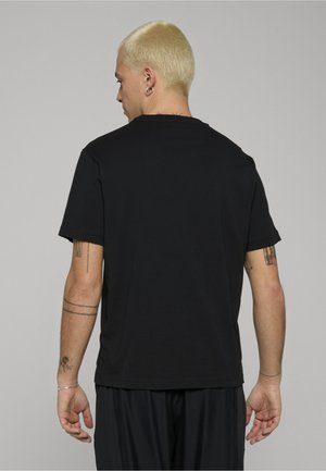 Camiseta de algodón negra con un corte relajado, mangas cortas y cuello redondo. Presenta una textura suave y sin logotipos o patrones visibles.