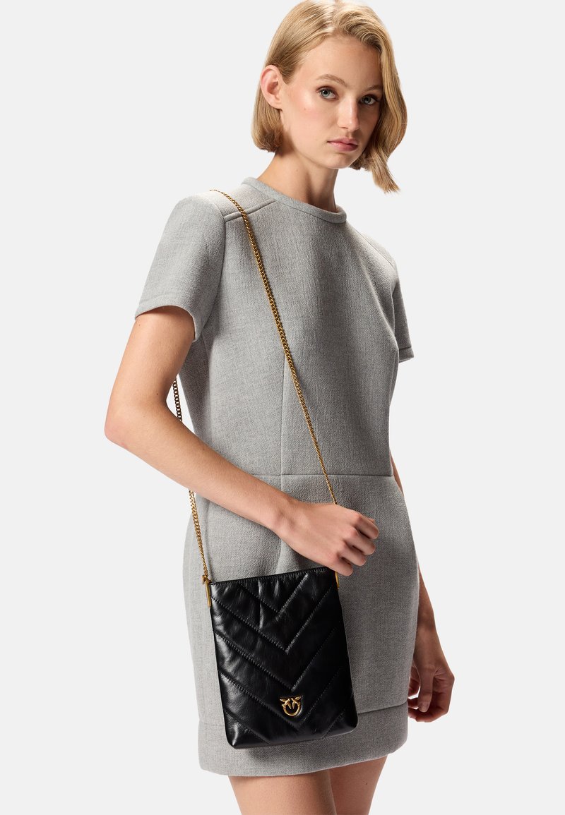 Borsa a tracolla in pelle matelassé nera con catena dorata, caratterizzata da un motivo a zigzag e un accento del logo dorato sulla parte anteriore.