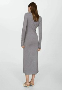 Robe grise à manches longues avec une silhouette ajustée, faite d'un tissu doux, s'étendant jusqu'au mollet. Elle présente un col rond et aucun motif visible.