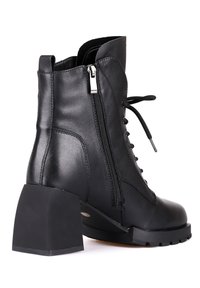 Bottine en cuir noir avec talon bloc, fermeture éclair latérale et lacets à l'avant, vue de profil extérieur sur fond blanc.