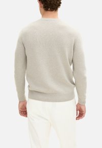 Lichtgrijze gebreide trui met lange mouwen, ribbelvormige ronde halslijn en ribbelmanchetten. Zachte textuur, aansluitend ontwerp en gemiddeld gewicht.