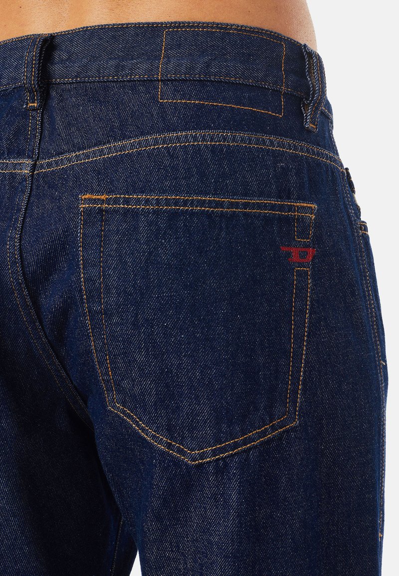 Dunkelblaue Denim-Jeans mit orangefarbenen Nähten. Verfügt über eine Gesäßtasche mit einem kleinen roten Logo. Schmaler Schnitt mit einer glatten Textur.