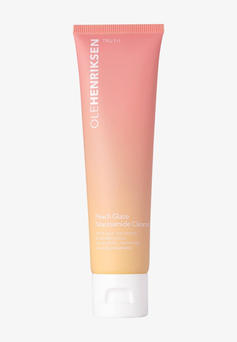 Pfirsichfarbene Tube des Ole Henriksen Peach Glaze Niacinamide Cleansers mit weißem Klappdeckel und Produktdetails auf der Vorderseite.