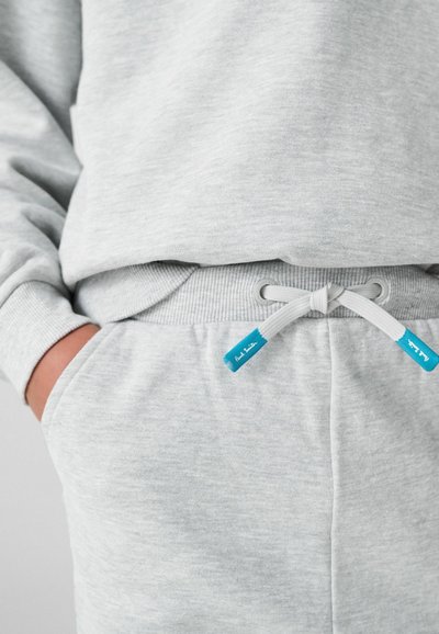 Šviesiai pilkas megztinis ir treningai pagaminti iš minkštos medžiagos. Yra įsiūti rankogaliai, virvutė su mėlyna akcentu ir šoniniai kišeniai.