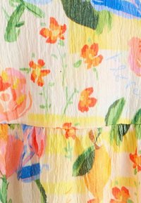 Blomsterprintet stof med gule, pink og orange blomster på en lys baggrund. Tekstureret med et krøllet udseende.