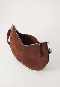 Borsa in suede marrone con design curvo, zip in argento e tracolla regolabile. L'interno è foderato in rosso. Presenta un piccolo dettaglio del logo.