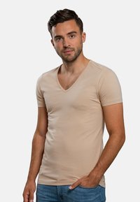 Beige v-hals t-shirt gemaakt van zachte stof, met korte mouwen, een aansluitend ontwerp, een gladde textuur en minimale stikseldetails.