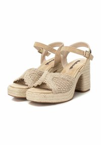 Sandalias de plataforma beige con una correa trenzada texturizada, correa ajustable en el tobillo y un tacón grueso envuelto. Material suave similar al ante.