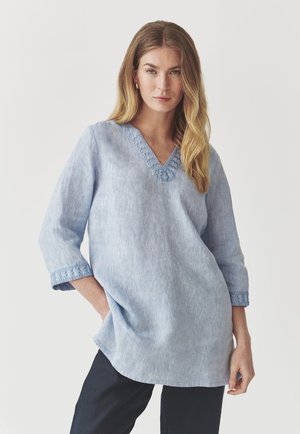 Tunic azzurro chiaro a maniche lunghe con scollo a V e dettagli ricamati. Realizzata in tessuto morbido, presenta una vestibilità ampia e tasche laterali.