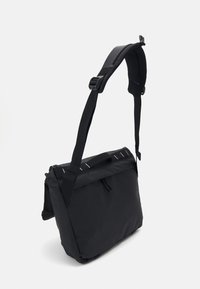 Borsa a tracolla nera con tracolla regolabile, forma rettangolare, chiusura con zip e dettagli foderati sulla parte anteriore per una maggiore eleganza.