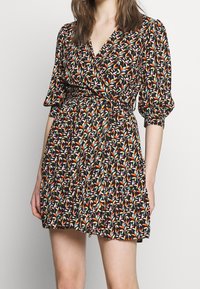 Robe portefeuille fleurie en tissu noir, ornée de motifs de feuillage colorés, avec des manches courtes bouffantes et un design de jupe à plusieurs niveaux.