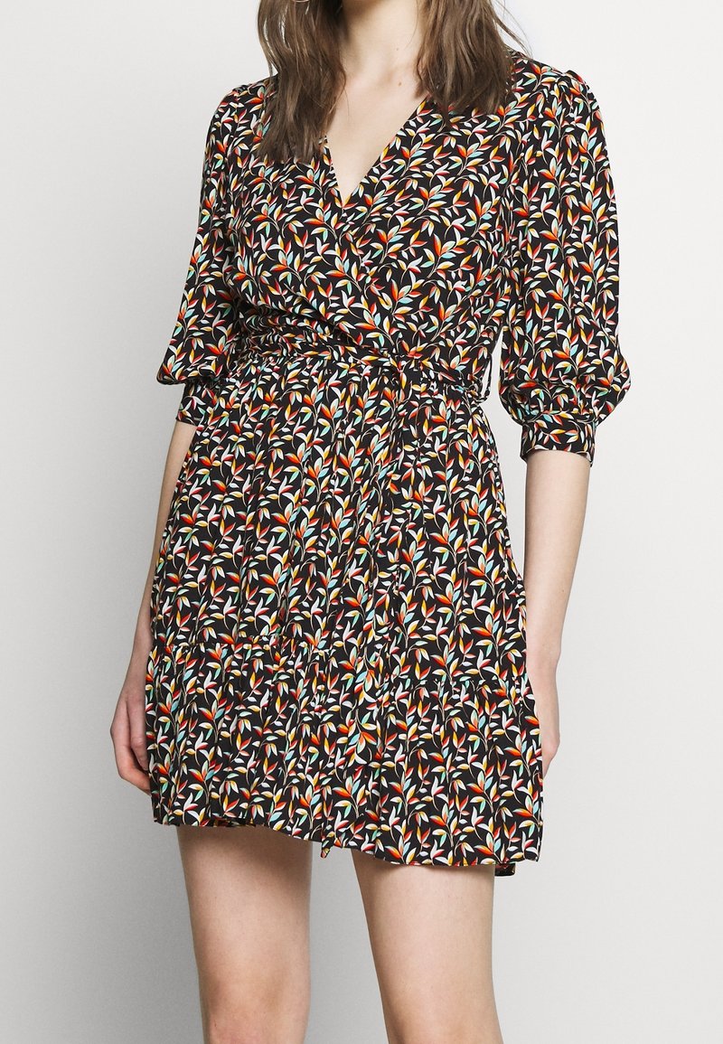 Robe portefeuille fleurie en tissu noir, ornée de motifs de feuillage colorés, avec des manches courtes bouffantes et un design de jupe à plusieurs niveaux.