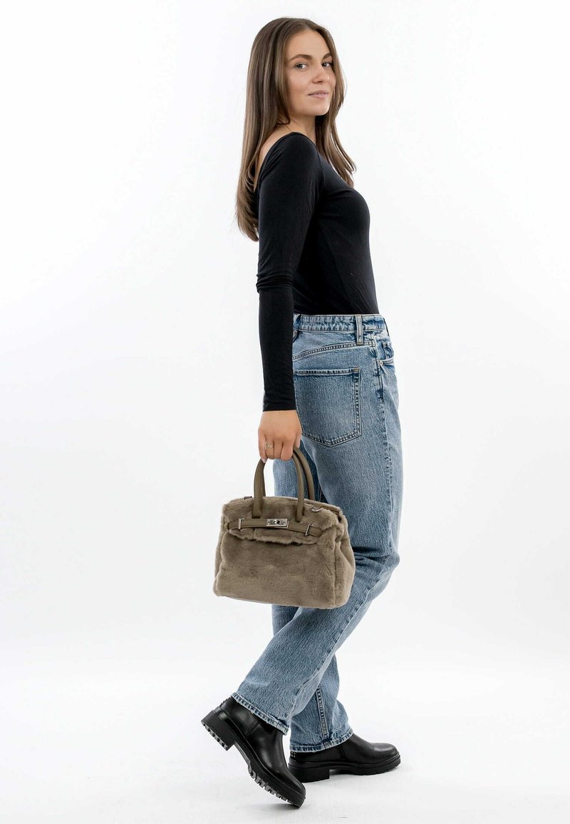 Grå pels håndtaske med dobbelte håndtag og sølvhardware, parret med blå højtaljede jeans og en sort langærmet top.