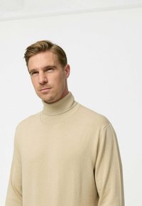 Beige garbónyakú pulóver, puha kötött anyagból készült, hosszú ujjú, testhezálló fazonú, bordás részletekkel a nyaknál.