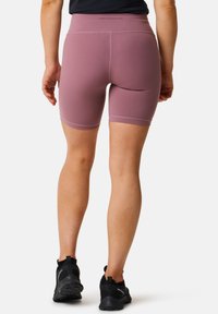 Lilla atletiske shorts med høj talje, glat tekstur og kontraststing, parret med sort fodtøj med en tekstureret sål.