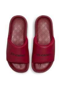 Sandales en caoutchouc rouge avec un semelle texturée, une large sangle supérieure et "AIR JORDAN" en lettres noires sur chaque sandale. Design élégant et moderne.