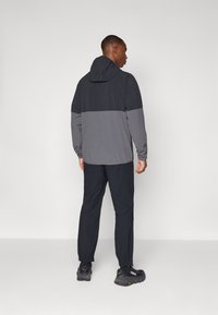 Herren Outdoor-Jacke in Dunkelgrau mit Kapuze, kombiniert mit passenden schwarzen Hosen; verfügt über elastische Bündchen und reflektierende Akzente.