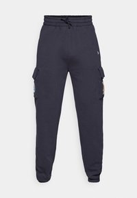 Mörkblå träningsoverallsbyxor med elastisk midja och dragsko. Har sidofickor med lock och avsmalnande manschetter vid ankeln.