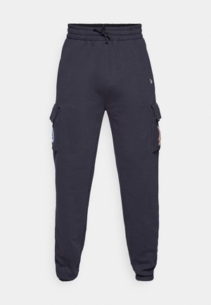 Námořnické tepláky s elastickým pasem a šňůrkou. Obsahují postranní cargo kapsy s klopami a zúžené manžety na kotnících.