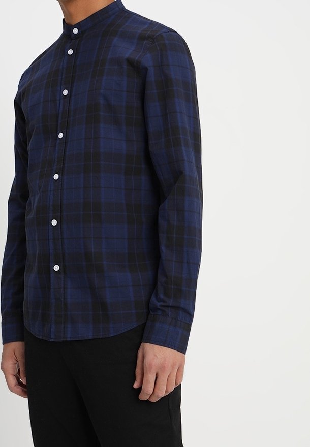 Camicia a quadri blu navy e nera con colletto alla coreana, maniche lunghe, tasca sul petto e bottoni bianchi. Tessuto di consistenza liscia.