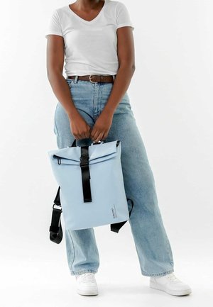 Jasnoniebieski wodoodporny plecak z rolowanym zamknięciem, czarnymi regulowanymi paskami i logo z przodu. Gładka faktura, prostokątny kształt.
