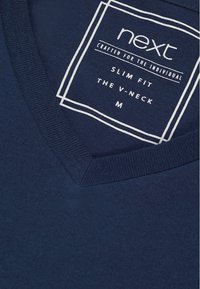 Tengerészkék, v-nyakú póló, Slim fit szabással. Bordás nyakkivágással rendelkezik, a gallér belsejében pedig egy anyagcímke tájékoztat a méretről és a márkáról.