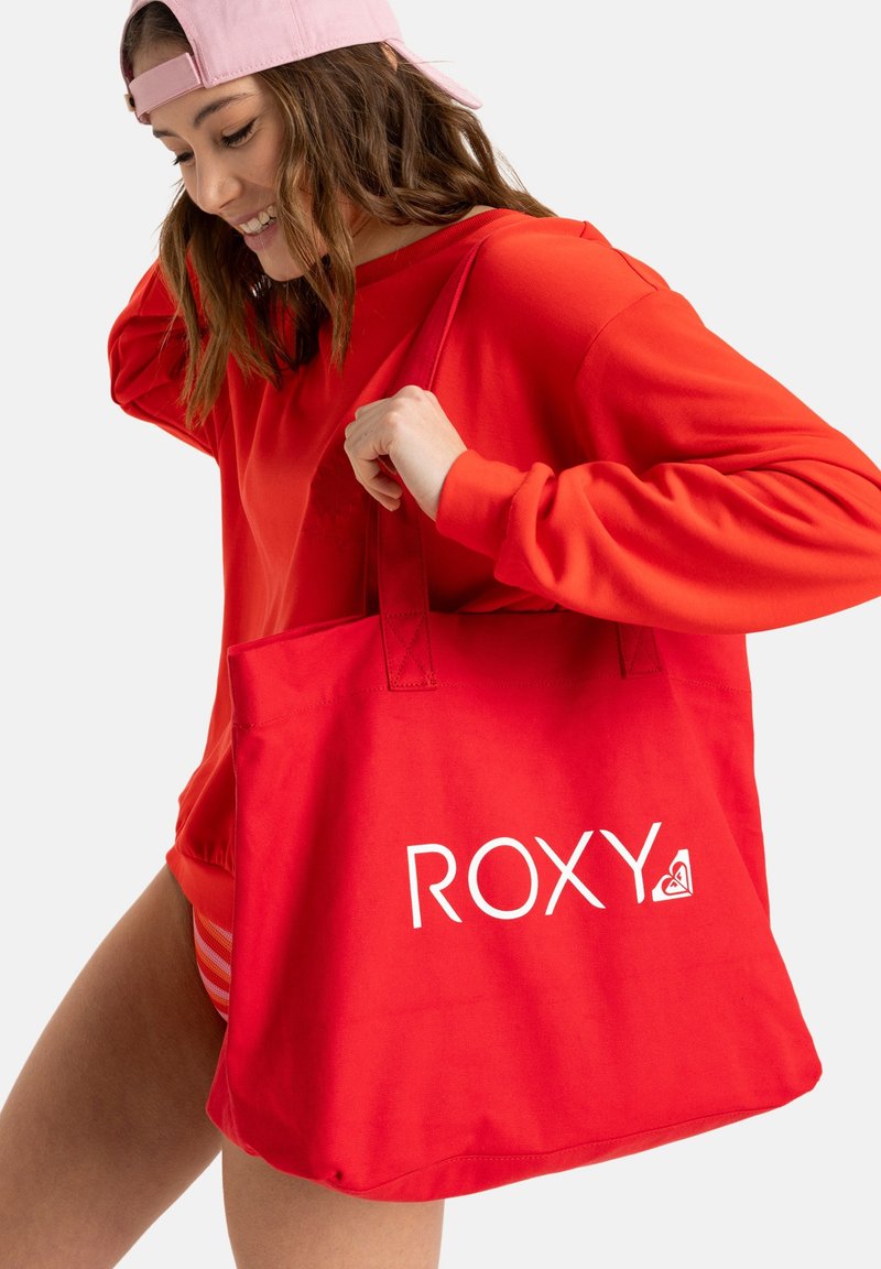 Rote Baumwolltasche mit dem weißen "ROXY"-Logo. Die Tasche hat stabile Griffe und ein geräumiges Design, das sich für den täglichen Gebrauch eignet.