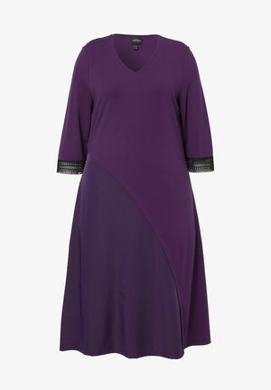 Fialové šaty s výstřihem do V, tříčtvrtečními rukávy a černou krajkou na manžetách. Rozšířený střih s asymetrickým panelem. Hladká textilie.