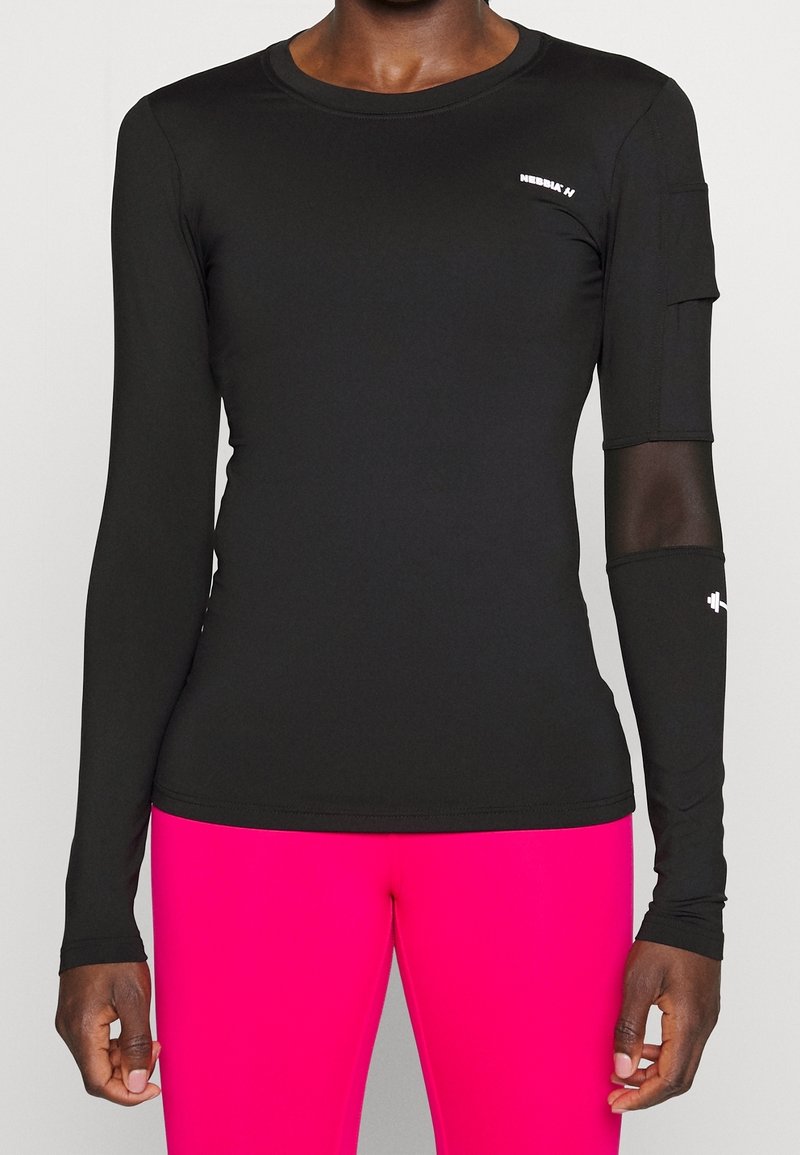 Schwarzes langärmliges Sportoberteil mit glatter Textur, ausgestattet mit einem Logo und einem Netz-Akzent am rechten Ärmel, kombiniert mit leuchtend pinkfarbenen Leggings.