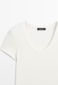 Weißes kurzärmeliges T-Shirt mit Rippstruktur, Rundhalsausschnitt und einem schwarzen Etikett am Kragen mit der Aufschrift "Massimo Dutti".