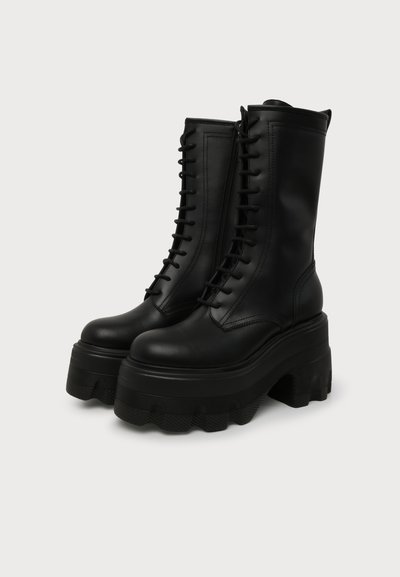 Bottes montantes en cuir noir à lacets avec semelles épaisses compensées et semelles à crampons, présentées côte à côte sur un fond clair uni.