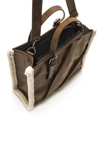 Sac à main en cuir marron avec des bordures en fourrure crémeuse et douce, doté de deux poignées supérieures, d'une fermeture éclair et de plusieurs compartiments intérieurs.