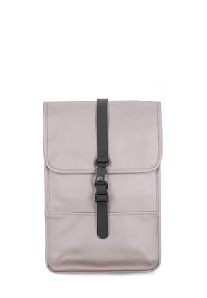 Mochila rosa claro con una textura suave, que presenta una solapa frontal, cierre de correa negra y un diseño minimalista.