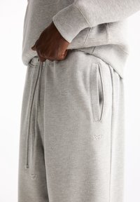 Graue Sweatpants aus weichem Baumwollmischgewebe. Mit Kordelzugbund, seitlichen Taschen und dezenten Logodetails auf dem Oberschenkel.