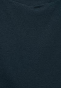 Närbild av mörkgrått stickat tyg med subtila veck och fint vävmönster.