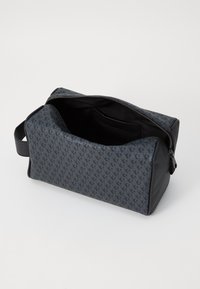 Borsa cosmetica grigio scuro con chiusura a zip, caratterizzata da un motivo ripetuto e sottile, texture liscia e una maniglia laterale per un facile trasporto.