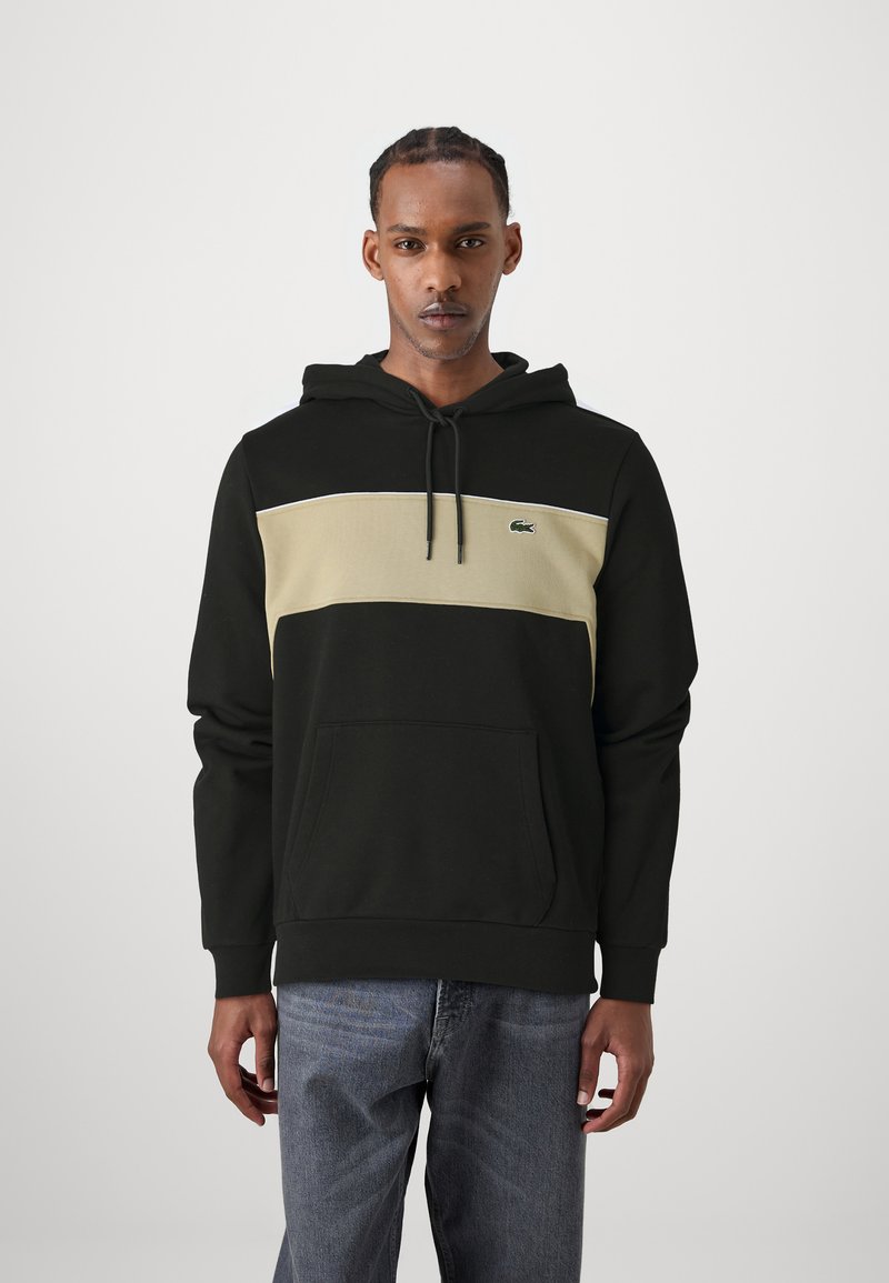 Haut à capuche en mélange de coton noir et beige avec un effet color-block. Il comporte une poche avant, une capuche ajustable et un petit logo sur la poitrine.