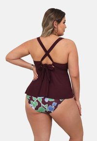 Bordeaux tankini-top met kruisbandjes en een strikdetail, gecombineerd met bikini-onderdelen met bloemenprint in donker bordeaux, groen en blauw.