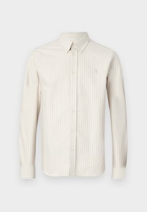 Ανοιχτό μπεζ πουκάμισο με ρίγες, με γιακά που κουμπώνει, μακριά μανίκια και μια διακριτική λογότυπη στο στήθος. Μαλακό ύφασμα με κάθετη ραφή.