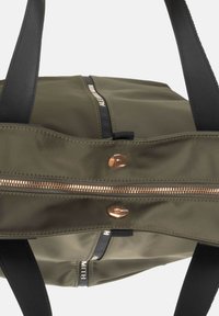 Borsa a tracolla in nylon verde oliva con manici in pelle nera, dotata di una cerniera in ottone e chiusura a scatto in metallo. Design minimalista con dettagli brandizzati.