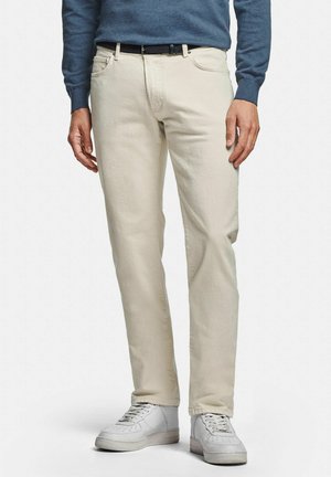 Beige Straight-Fit-Jeans aus Baumwolle mit fünf Taschen, Gürtelschlaufen und weicher Textur, kombiniert mit weißen Sneakers.