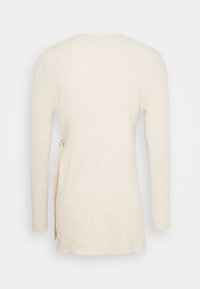 Pull beige à manches longues en maille côtelée avec un détail noué sur le côté, présenté de dos sur un fond uni.