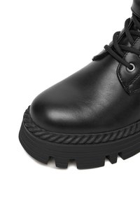 Czarne skórzane botki za kostkę z okrągłym noskiem, grubą teksturowaną podeszwą z akcentem w postaci liny oraz czarnymi sznurówkami przez srebrne oczka.