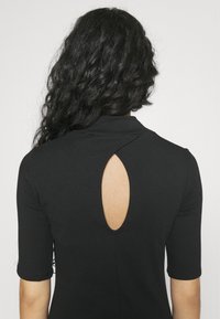 Svart, kortärmad topp med en låg ryggutskärning och krage. Slät textur med en figurnära silhuett.