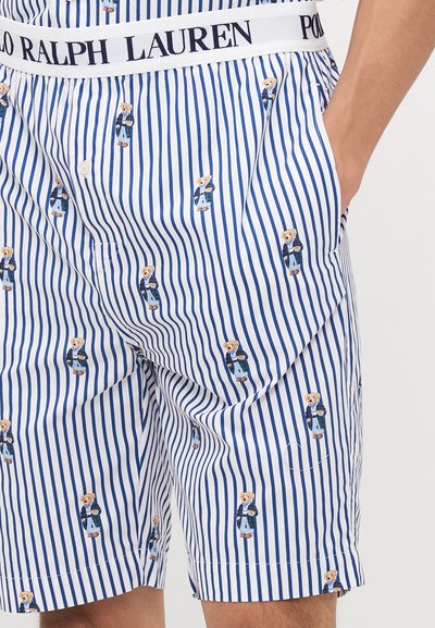 Shorts rayés bleu et blanc avec une texture en coton doux, comportant de petits motifs d'ours et une taille avec logo pour plus de détail.