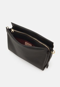 Sort læder clutch taske med tekstureret overflade, guld lynlås og rummeligt indre. Har en bordeaux foring og et dekorativt mærke indeni.