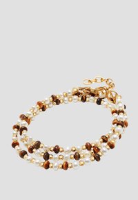 Triple-strand bracelet with alternating white pearls, brown beads, and small gold beads, featuring a gold chain clasp on gray background.