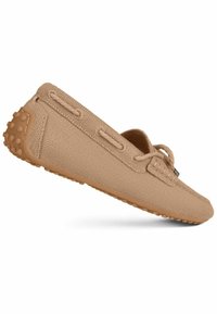 Hellbraunes Slip-on-Schuh mit einem strukturierten Stoffobermaterial, leichtem Design, weichen Schnürdetails und einer Gummisohle mit kleinen Griffnoppen.